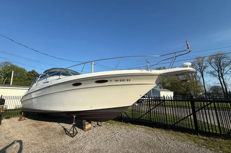 Slide: The Image of 1996 Sea Ray Sundancer 330 boat on stands, parked outdoors under clear blue sky. - 22