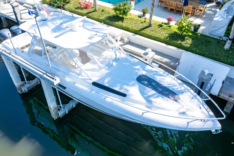 Slide: The Image of 2016 Intrepid 400 Cuddy boat docked by a waterfront patio. - 4