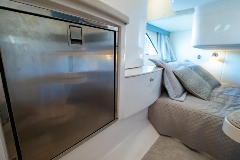 Slide: The Image of Interior of 2016 Intrepid 400 Cuddy, featuring a cozy bed and stainless steel appliance. - 44