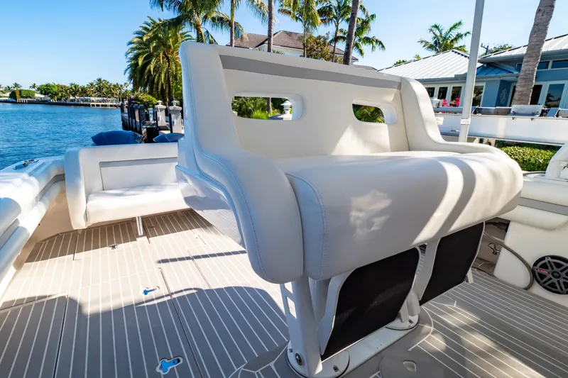 Slide: The Image of 2016 Intrepid 400 Cuddy boat interior with white seating, docked by palm trees. - 47