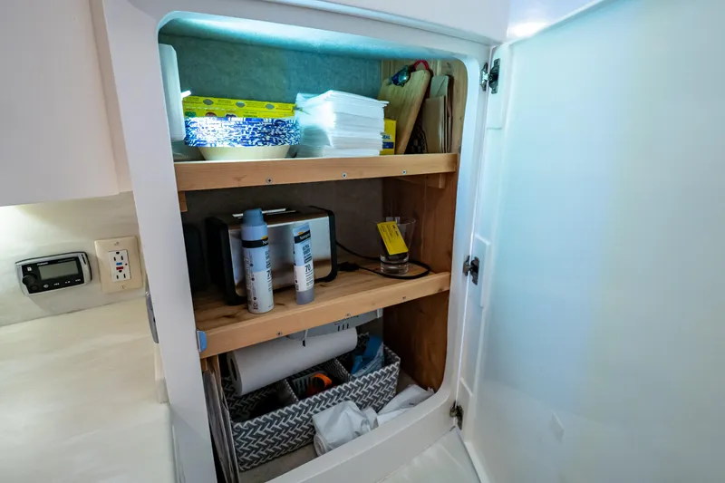 Slide: The Image of Cabinet storage inside a 2016 Intrepid 400 Cuddy boat, featuring shelves with various items. - 49