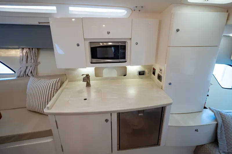 Slide: The Image of 2016 Intrepid 400 Cuddy interior with kitchenette, microwave, and seating area. - 8