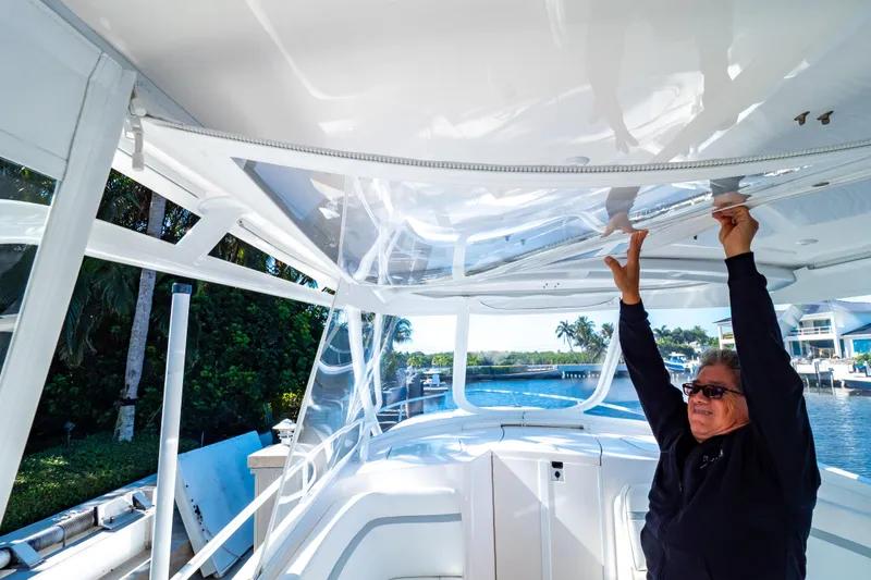 Slide: The Image of Man adjusting canopy on 2016 Intrepid 400 Cuddy boat, docked near tropical scenery. - 80