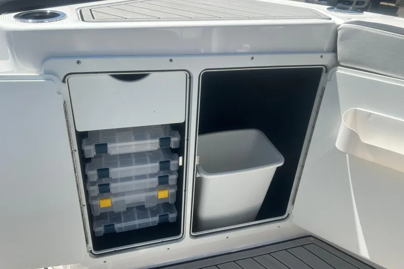 Slide: The Image of 2024 Yamaha Boats 252 FSH Sport storage compartments with tackle boxes and trash bin. - 14