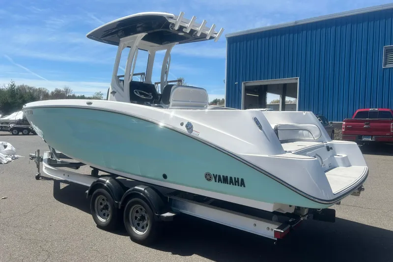 Slide: The Image of 2024 Yamaha Boats 252 FSH Sport on trailer, parked outdoors near blue building. - 3