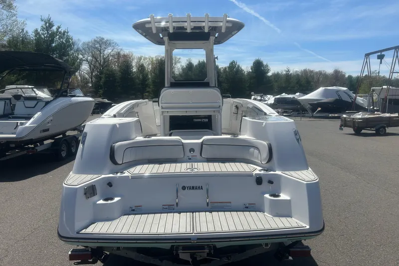 Slide: The Image of 2024 Yamaha Boats 252 FSH Sport, rear view, in a marina setting. - 5