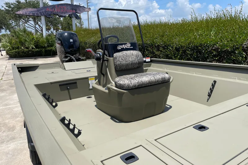 Slide: The Image of 2026 Tracker Grizzly 2072 CC boat with camouflage seating, parked near "Live Alligators" sign. - 46