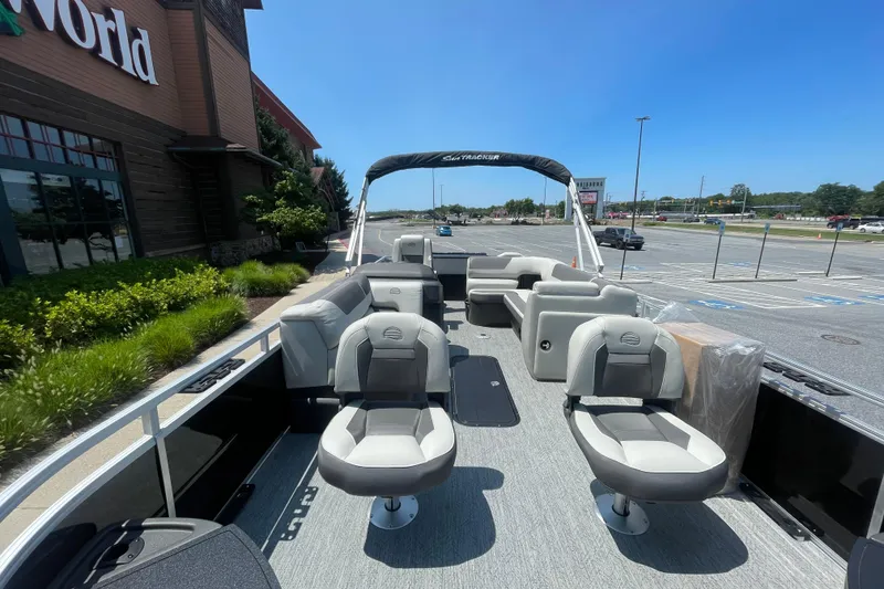 Slide: The Image of 2026 Sun Tracker Fishin' Barge 22 XP3 pontoon boat with seating, parked outside a store. - 2