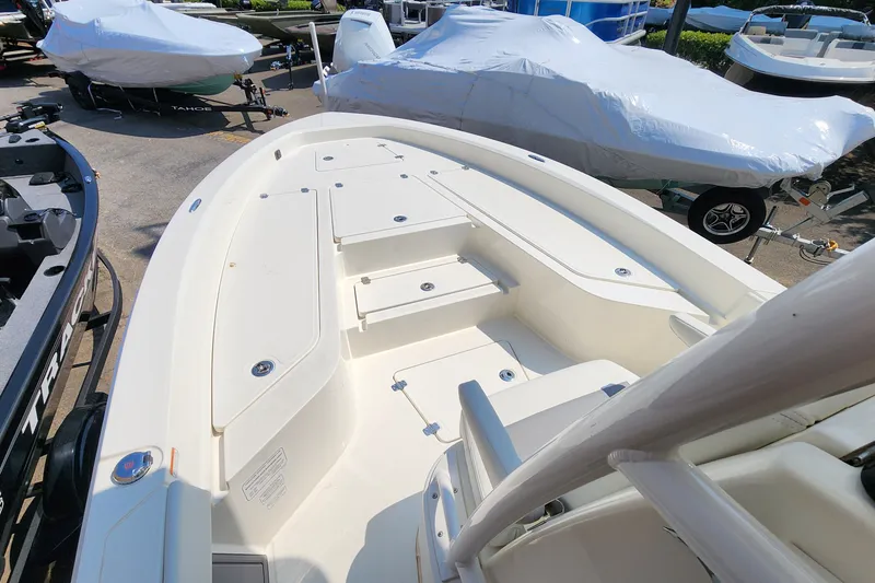 Slide: The Image of 2026 Mako 24 APEX boat deck, spacious seating, and storage compartments in a showroom setting. - 5