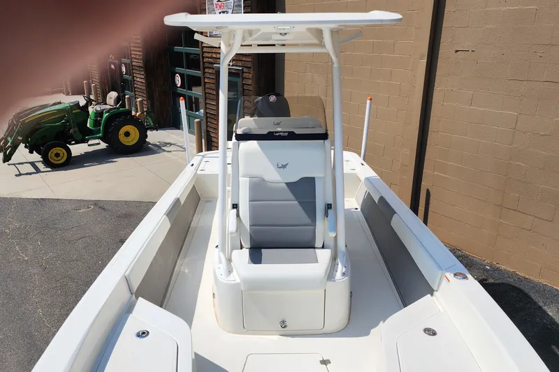 Slide: The Image of 2026 Mako 24 APEX boat with seating, parked near a green tractor. - 4