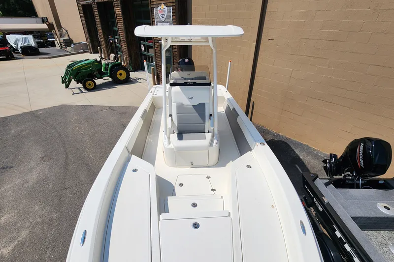 Slide: The Image of 2026 Mako 24 APEX boat with Mercury engine, parked near a tractor. - 3