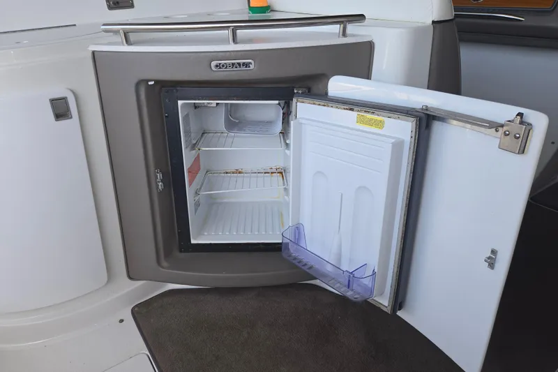 Slide: The Image of Open mini fridge on 2001 Cobalt 292 boat, showing interior shelves and door storage. - 12