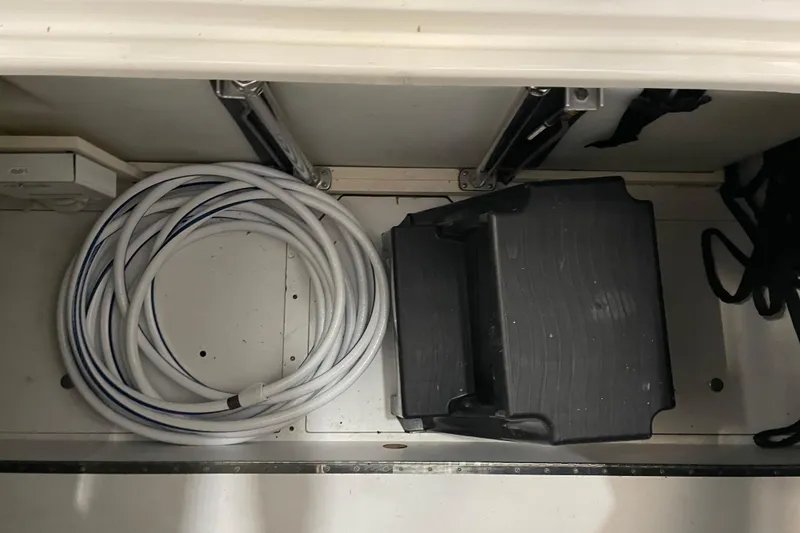 Slide: The Image of Storage compartment in a 2004 Carver 420 Mariner with coiled hose and black container. - 19