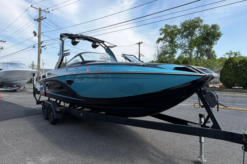 Slide: The Image of 2020 Centurion Ri237 boat on trailer, parked outdoors, blue and black design. - 5