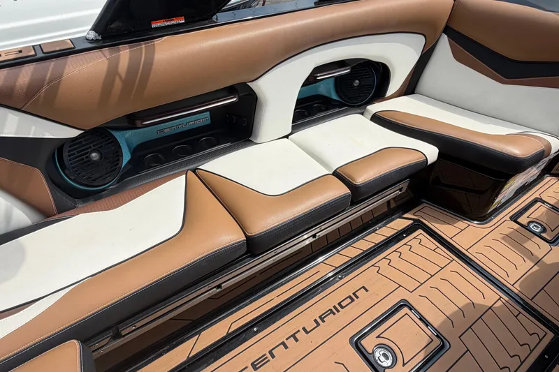 Slide: The Image of 2020 Centurion Ri237 boat interior with brown and white seating, featuring branded flooring. - 9