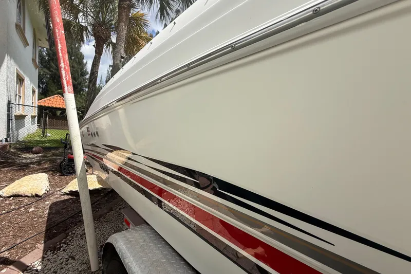 Slide: The Image of 2001 Wellcraft 29 Scarab Sport Open boat side view with sleek design and vibrant stripes. - 23