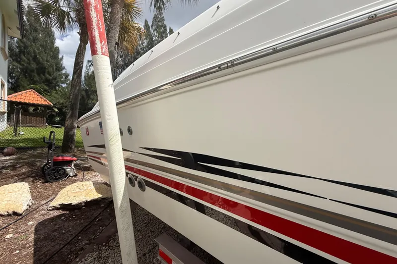 Slide: The Image of 2001 Wellcraft 29 Scarab Sport Open boat with sleek red and black stripes, parked outdoors. - 24