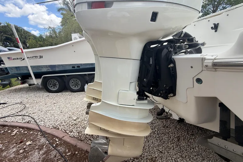 Slide: The Image of 2001 Wellcraft 29 Scarab Sport Open boat engine, parked on gravel with trailer in background. - 34