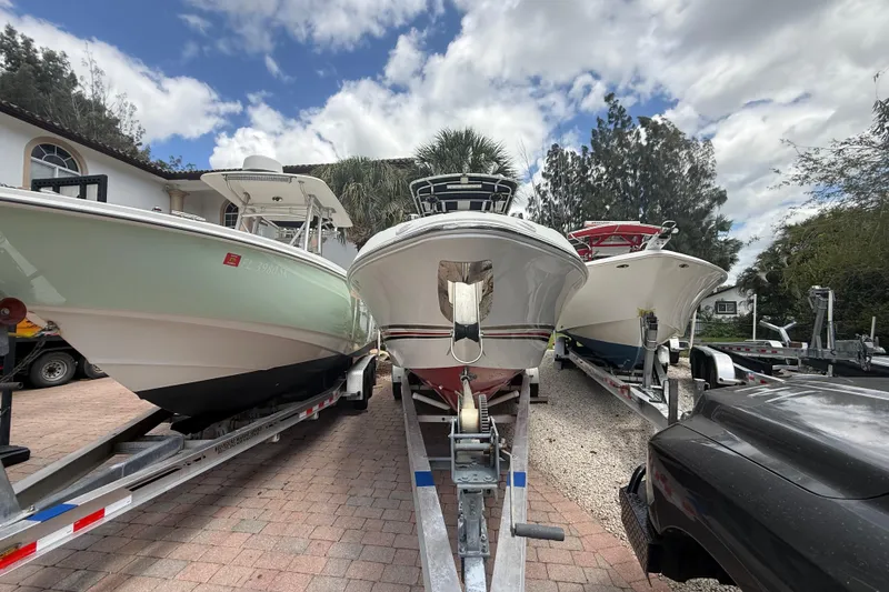 Slide: The Image of 2001 Wellcraft 29 Scarab Sport Open boat on trailer, flanked by two other boats, under a cloudy sky. - 41