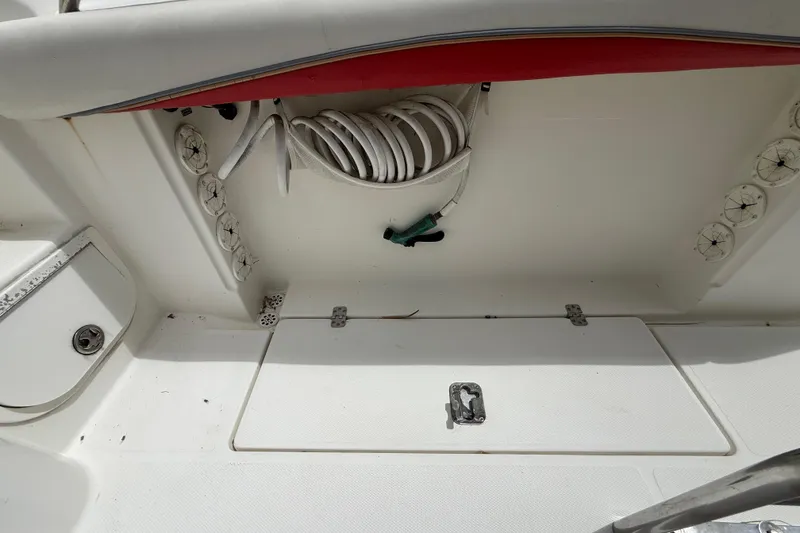 Slide: The Image of 2001 Wellcraft 29 Scarab Sport Open boat interior with coiled hose and storage compartment. - 54