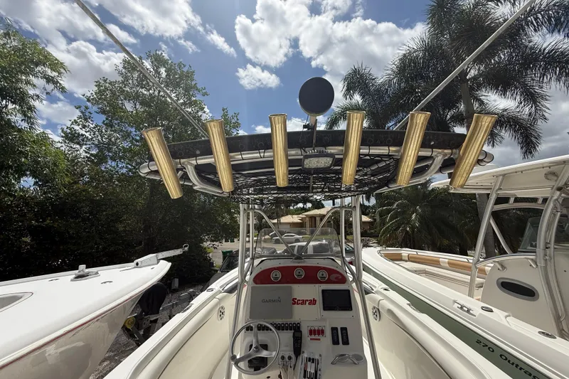 Slide: The Image of 2001 Wellcraft 29 Scarab Sport Open boat with rod holders, steering wheel, and console under a sunny sky. - 60