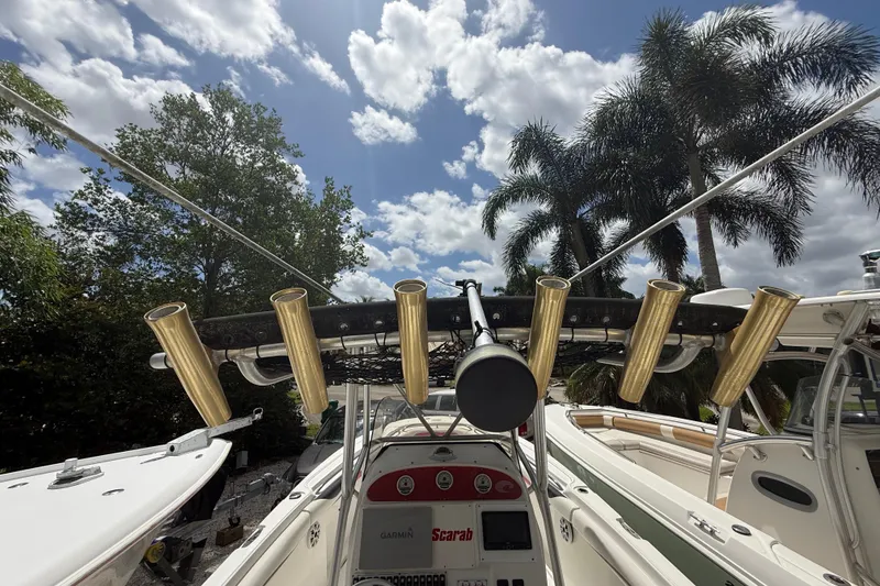 Slide: The Image of 2001 Wellcraft 29 Scarab Sport Open boat with rod holders, under a sunny sky with palm trees. - 61