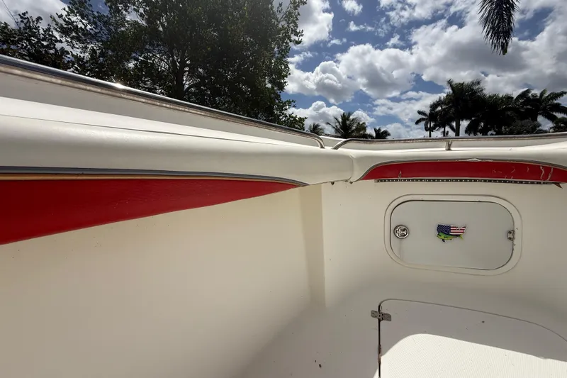 Slide: The Image of 2001 Wellcraft 29 Scarab Sport Open boat interior with red accents under a cloudy sky. - 86