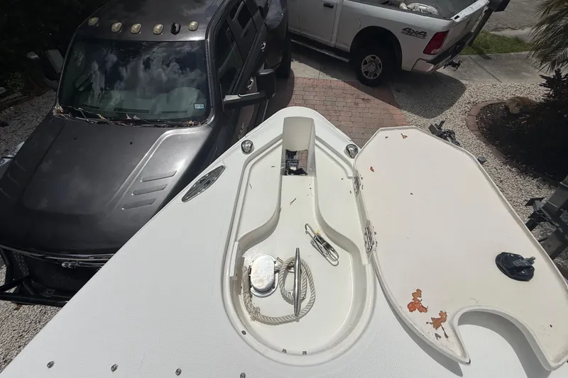 Slide: The Image of 2001 Wellcraft 29 Scarab Sport Open boat with anchor storage, parked near two vehicles. - 96