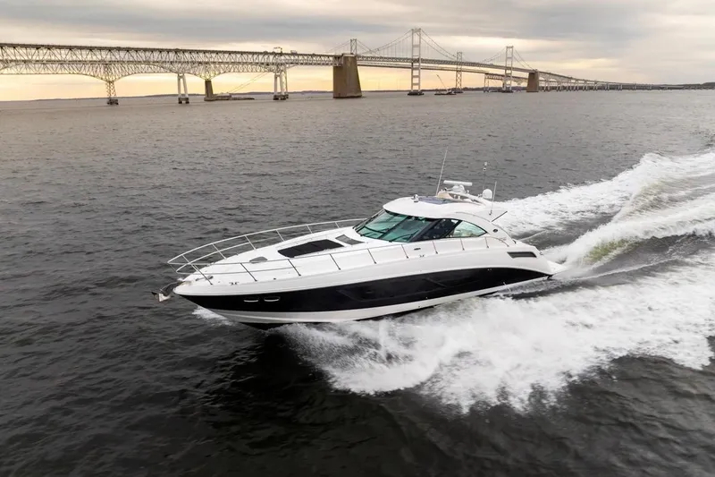 The Image of 2013 Sea Ray Sundancer 540 cruising near a large bridge at sunset. - 0