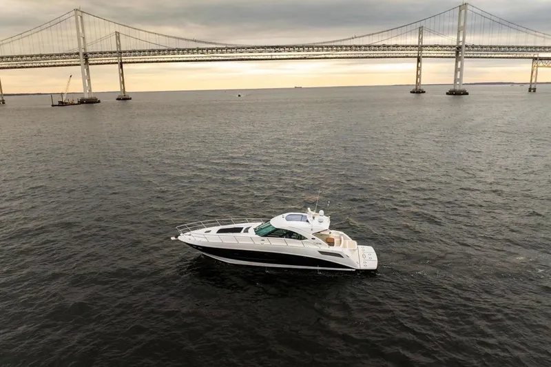 Slide: The Image of 2013 Sea Ray Sundancer 540 yacht cruising under a bridge at sunset. - 6