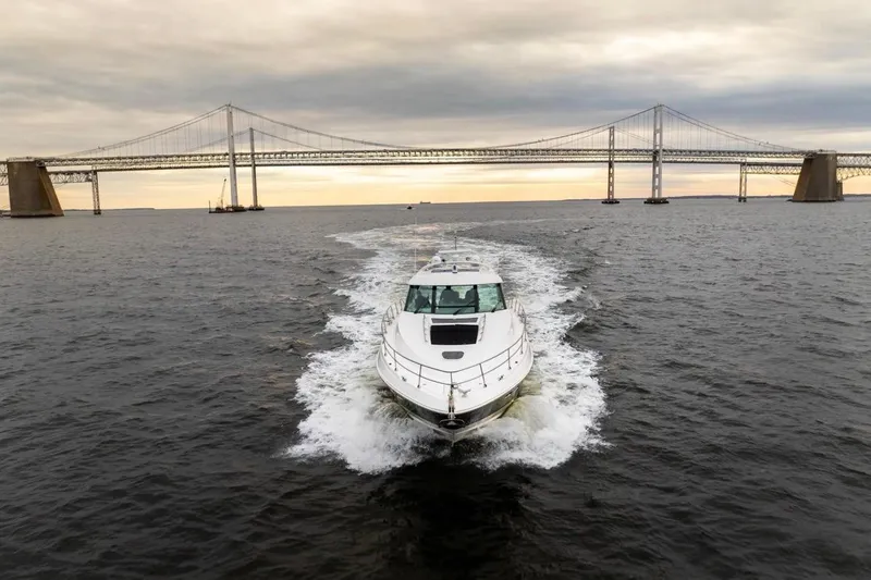 Slide: The Image of 2013 Sea Ray Sundancer 540 cruising under a large bridge at sunset. - 7