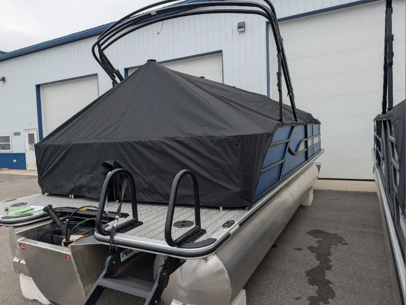 Slide: The Image of 2026 Bentley Legacy 223 pontoon boat with cover, parked outside a building. - 5