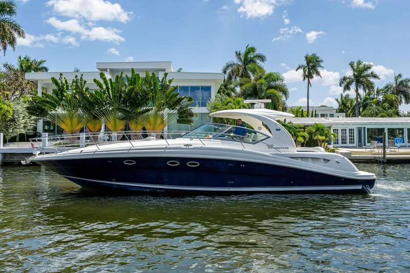 The Image of 2005 Sea Ray 420 Sundancer yacht cruising near waterfront property with palm trees. - 0