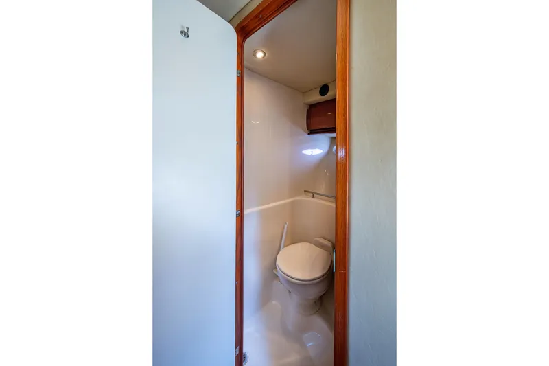 Slide: The Image of 2005 Sea Ray 420 Sundancer yacht bathroom interior with wooden door and compact toilet. - 22