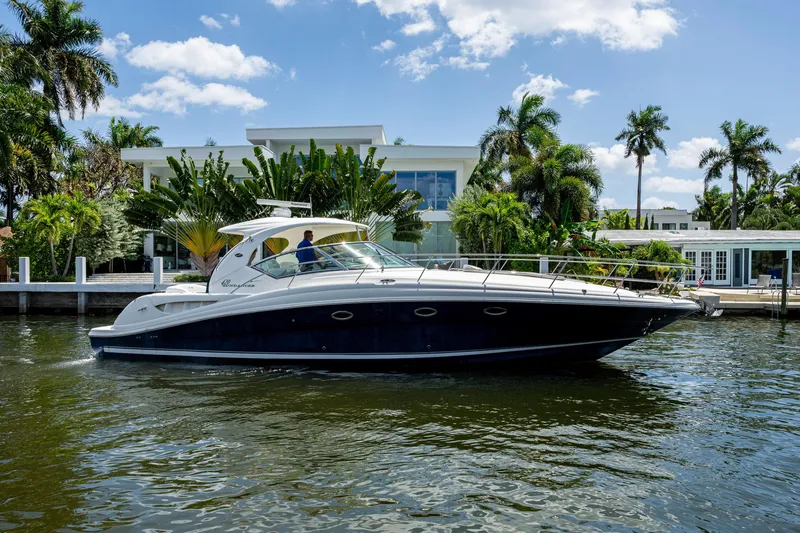 Slide: The Image of 2005 Sea Ray 420 Sundancer yacht cruising near waterfront homes, surrounded by palm trees. - 3