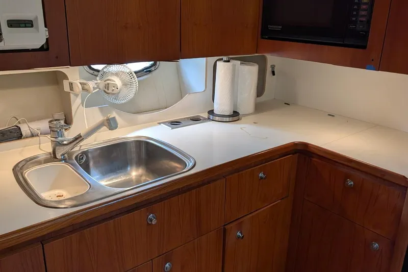 Slide: The Image of Kitchen area of a 1998 Tiara Yachts 4100 Open, featuring sink and wooden cabinetry. - 15