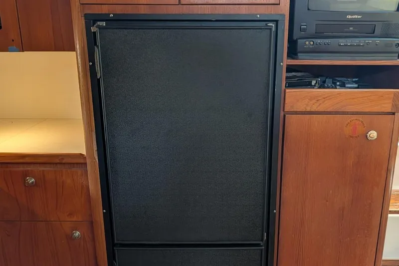 Slide: The Image of Wooden cabinetry with a black refrigerator in a 1998 Tiara Yachts 4100 Open. - 16