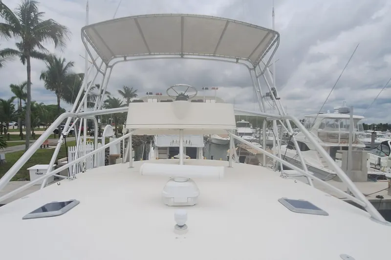 Slide: The Image of 1998 Tiara Yachts 4100 Open boat docked at marina with palm trees and cloudy sky. - 8