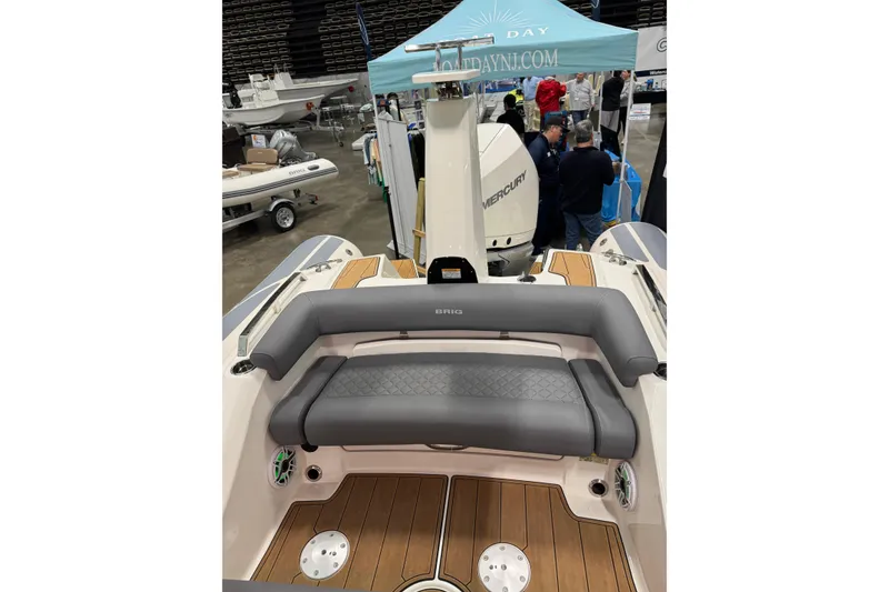Slide: The Image of 2026 Brig Eagle 6.7 boat interior with gray seating and wood flooring at a boat show. - 18