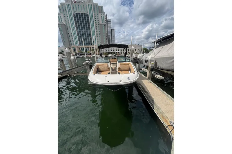 Slide: The Image of 2019 Sea Ray SDX 270 Outboard docked at marina with cityscape backdrop. - 2