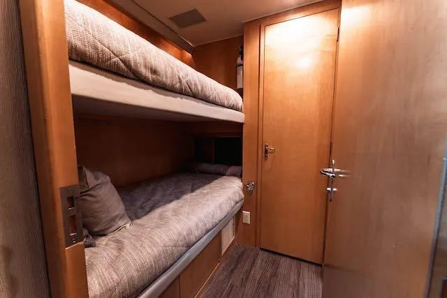 Slide: The Image of 1999 Hatteras 74 Sport Deck Motor Yacht cabin with wooden bunk beds and ladder. - 28