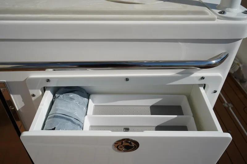 Slide: The Image of 2024 Edgewater 285CC boat storage compartment with open drawer and packaged item. - 11