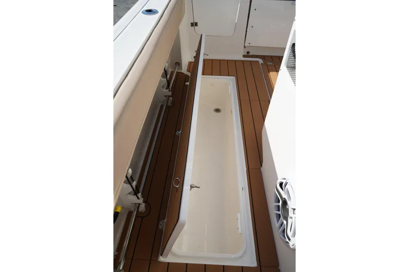 Slide: The Image of 2024 Edgewater 285CC boat interior with open storage compartment and teak flooring. - 16
