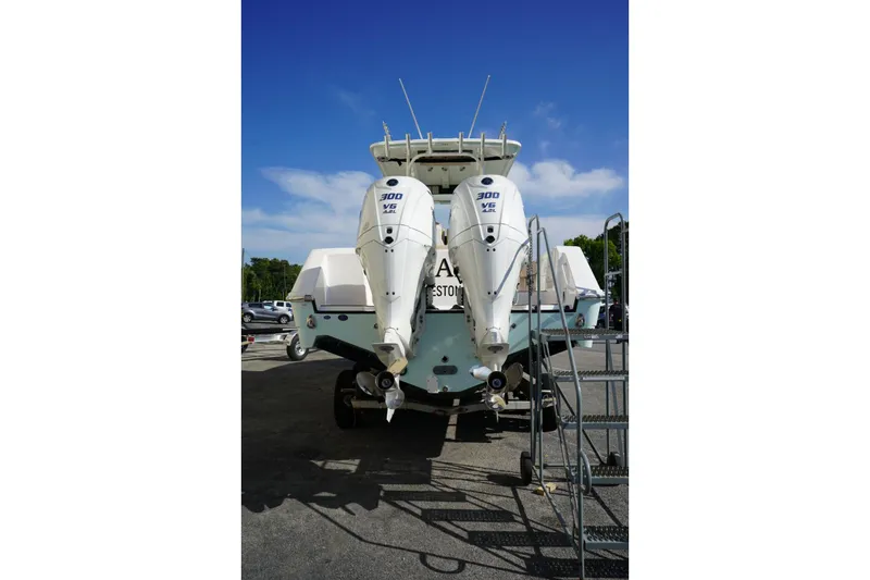 Slide: The Image of 2024 Edgewater 285CC boat with dual 300 V6 engines, parked outdoors under a clear blue sky. - 2
