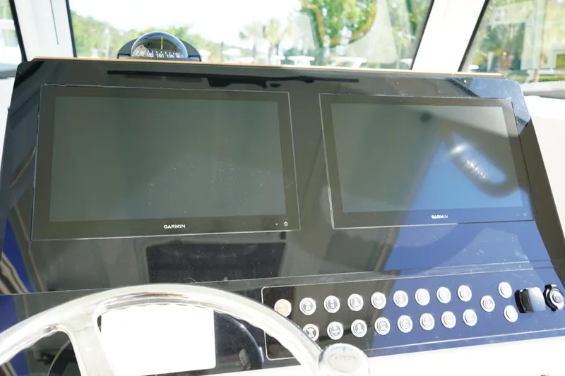 Slide: The Image of 2024 Edgewater 285CC boat dashboard with dual Garmin displays and control buttons. - 22