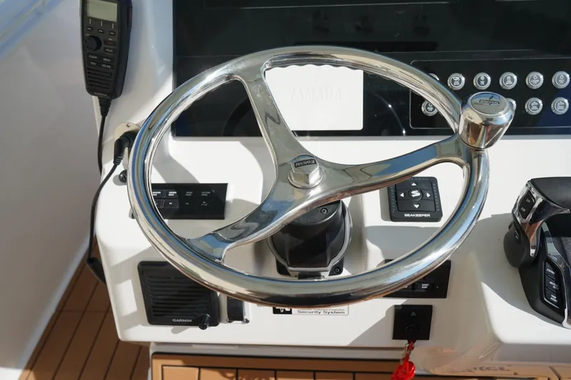 Slide: The Image of Steering wheel of 2024 Edgewater 285CC boat with control panel and radio. - 24
