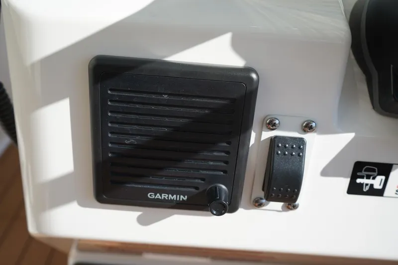 Slide: The Image of Garmin speaker on 2024 Edgewater 285CC boat dashboard, featuring control knob and switch. - 28
