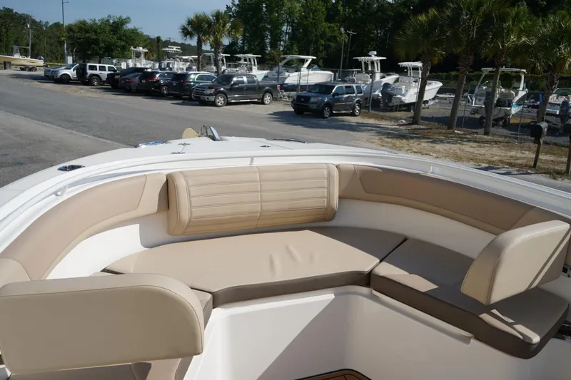 Slide: The Image of 2024 Edgewater 285CC boat with beige seating, parked near other boats and vehicles. - 33
