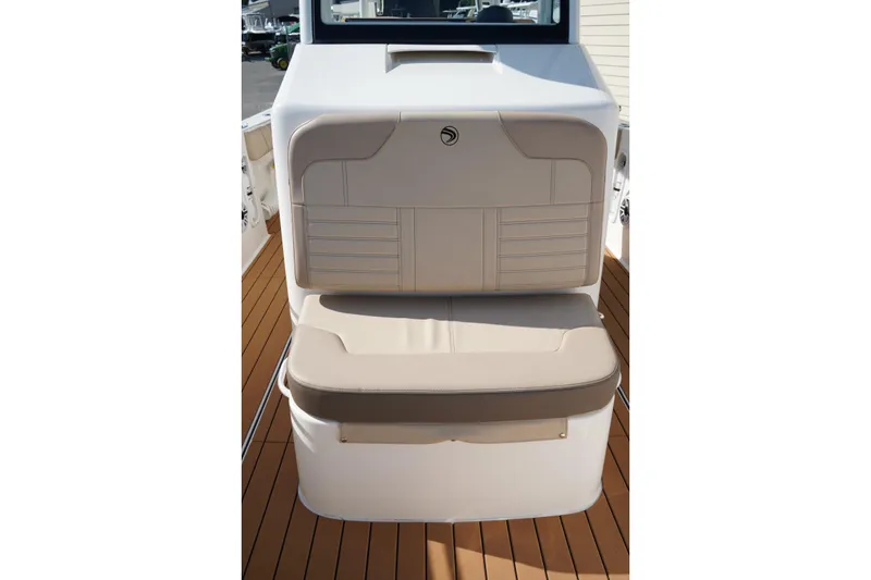 Slide: The Image of 2024 Edgewater 285CC boat seating with beige cushions on a wooden deck. - 38