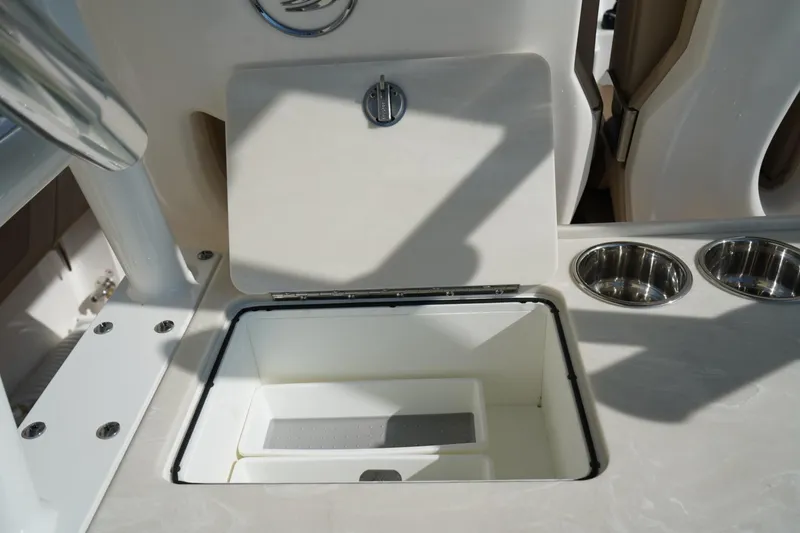 Slide: The Image of 2024 Edgewater 285CC boat interior with open storage compartment and cup holders. - 7